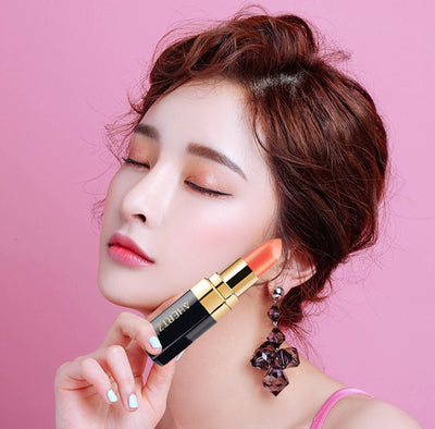 Euphorale lipstick Shopify in a model's hand against a pink background, showcasing a vibrant lipstick shade.